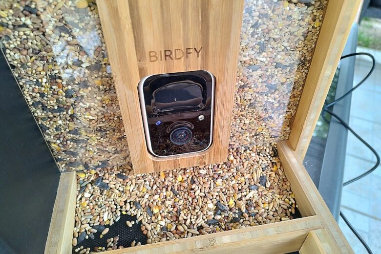 La mangeoire connectée Birdfy en bambou remplie de graines, prête à accueillir les premiers visiteurs ailés.
