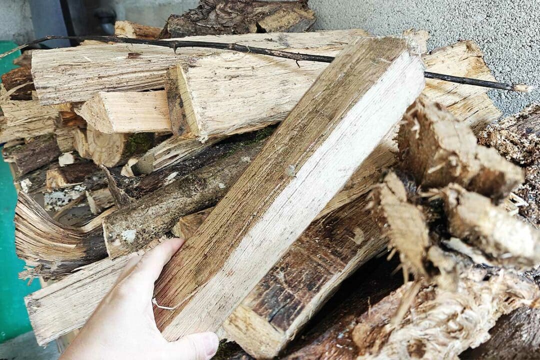 Un tas de bois et une buche tenue dans la main.
