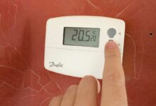 Une personne règle la température sur son thermostat.