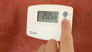 Une personne règle la température sur son thermostat.