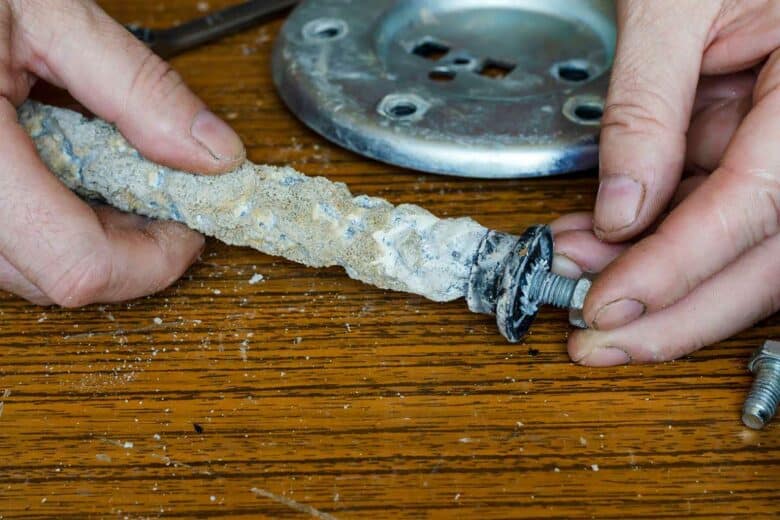 Un homme change l'anode de son chauffe-eau.