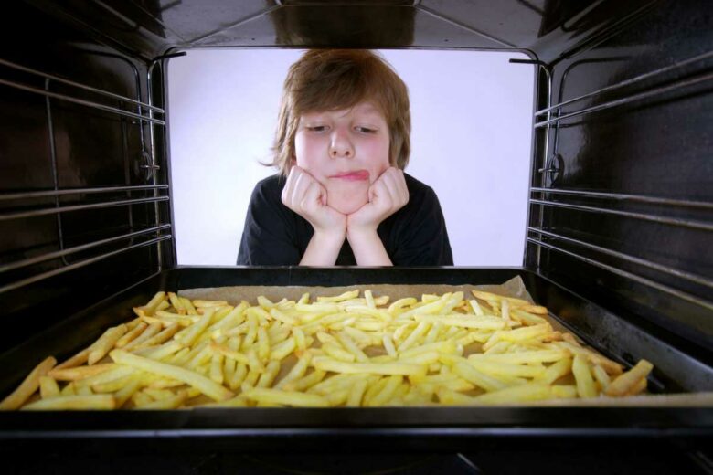 Un enfant salive devant les frites au four.
