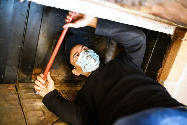 Un professionnel effectue le ramonage d'une cheminée.