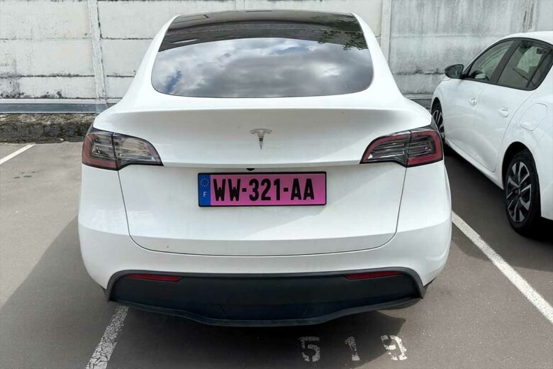 Une voiture avec une plaque provisoire rose.