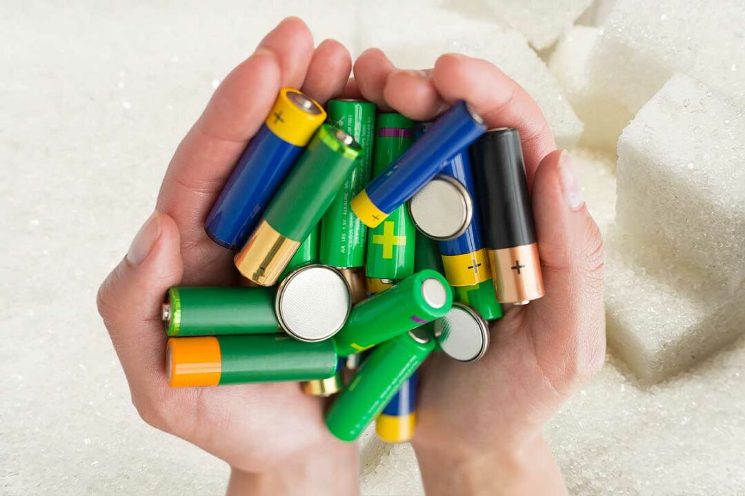 Des mains tiennent des piles au-dessus de sucre.