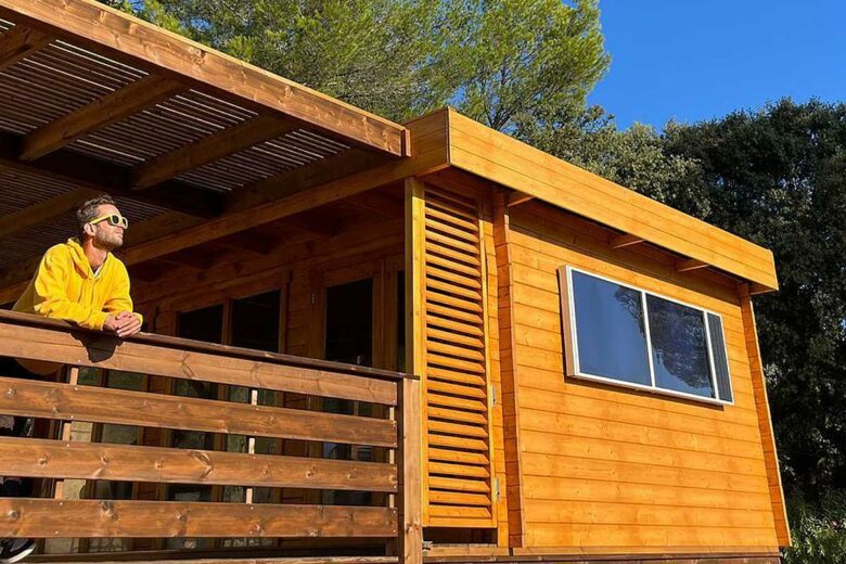 Un chauffage solaire sur la façade d'une maison bardée de bois.