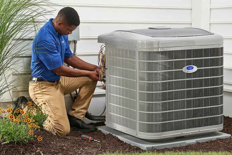 Un homme installe une unité extérieure de climatisation.