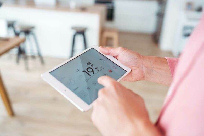 Un homme pilote son chauffage depuis sa tablette.
