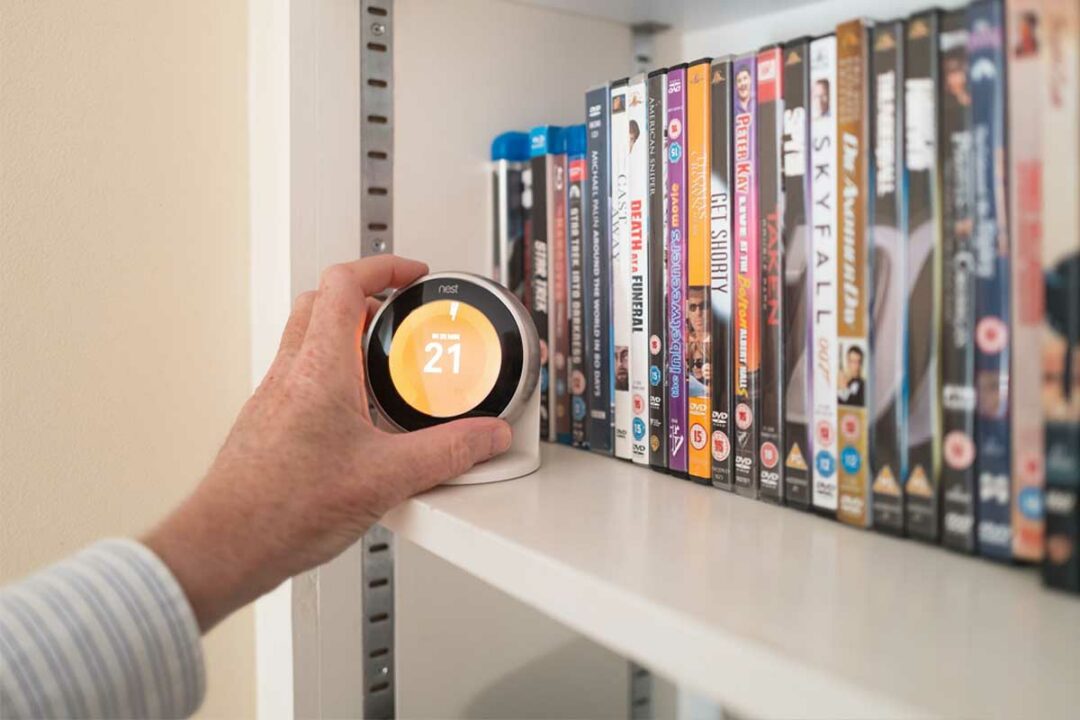 Une personne ajuste son chauffage avec un thermostat connecté.