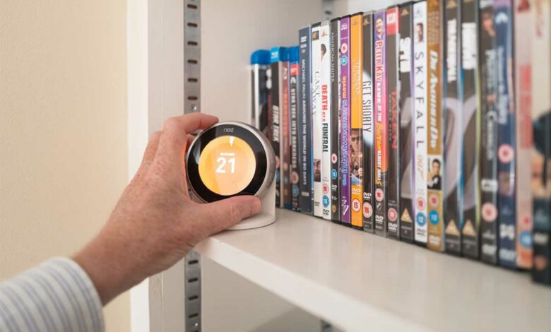 Une personne ajuste son chauffage avec un thermostat connecté.