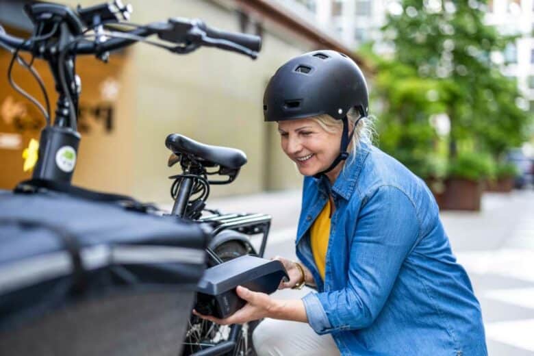Une femme installe la batterie de son vélo électrique.