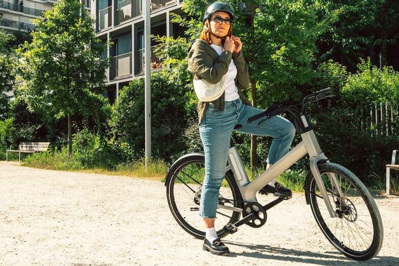 Une femme met son casque sur son vélo.