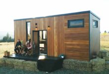 Un couple boit son café sur la terrasse de sa tiny house.