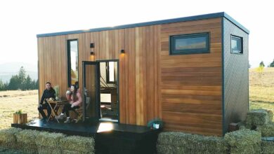 Un couple boit son café sur la terrasse de sa tiny house.