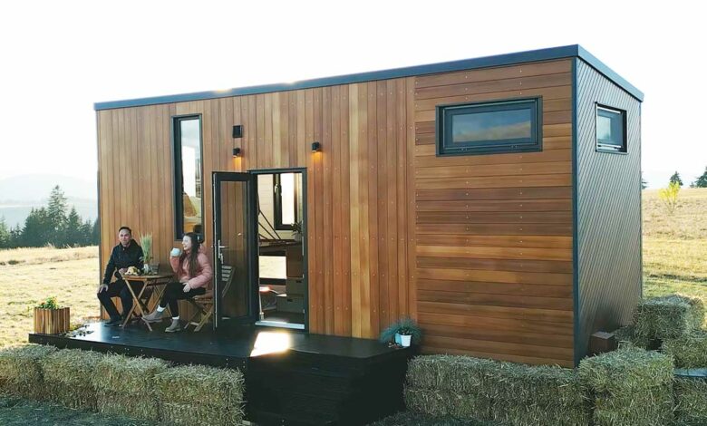 Un couple boit son café sur la terrasse de sa tiny house.