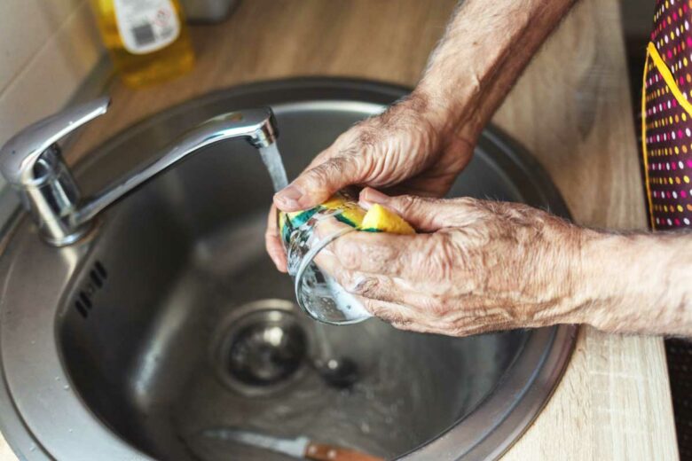 Une personne agée fait la vaisselle.
