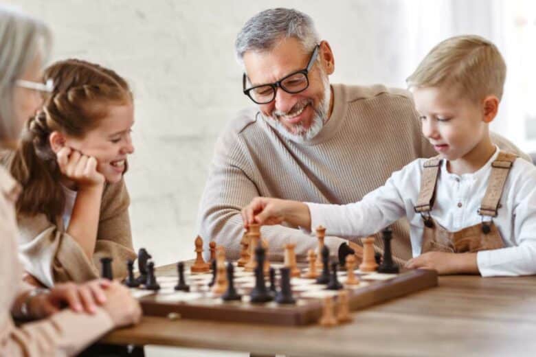 Un enfant joue aux échecs avec des adultes.