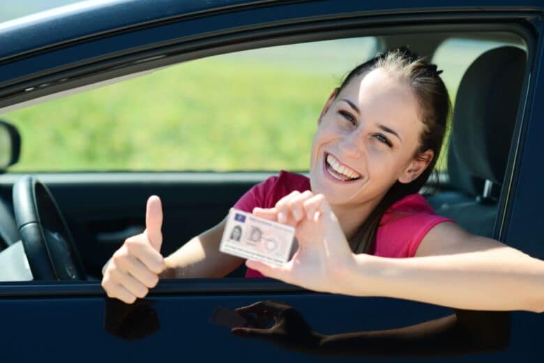 Une jeune femme montre son permis au volant d'une voiture.