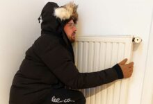 Un homme frigorifié contre un chauffage.