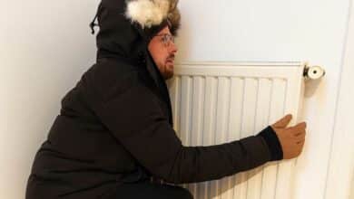 Un homme frigorifié contre un chauffage.