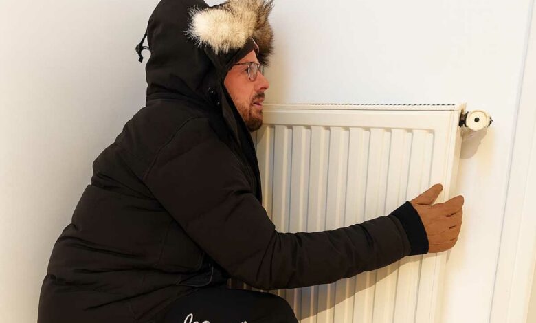 Un homme frigorifié contre un chauffage.
