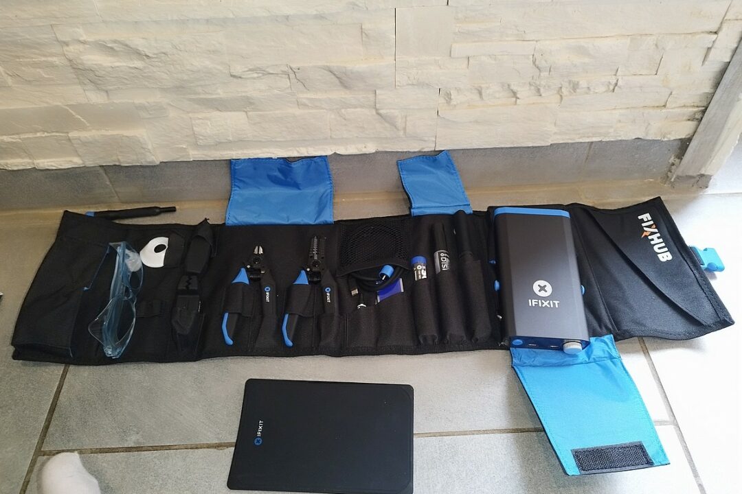 Détail des outils inclus dans le kit FixHub d’iFixit : pinces, câble USB-C et accessoires bien organisés.