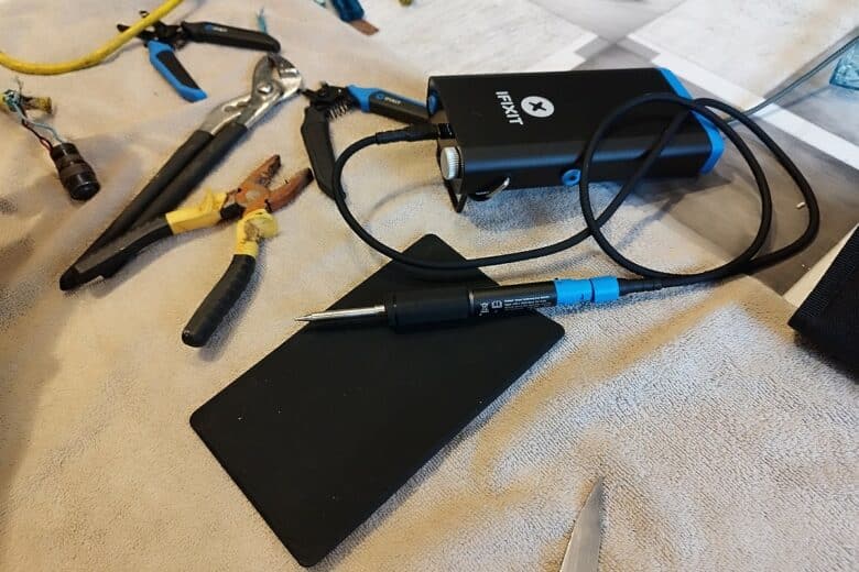 Le fer à souder électronique du kit FixHub d’iFixit en action installé sur une table de bricolage.