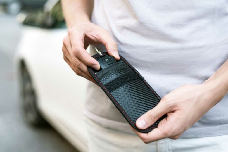 Un homme range sa clé de voiture dans une pochette anti RFID.