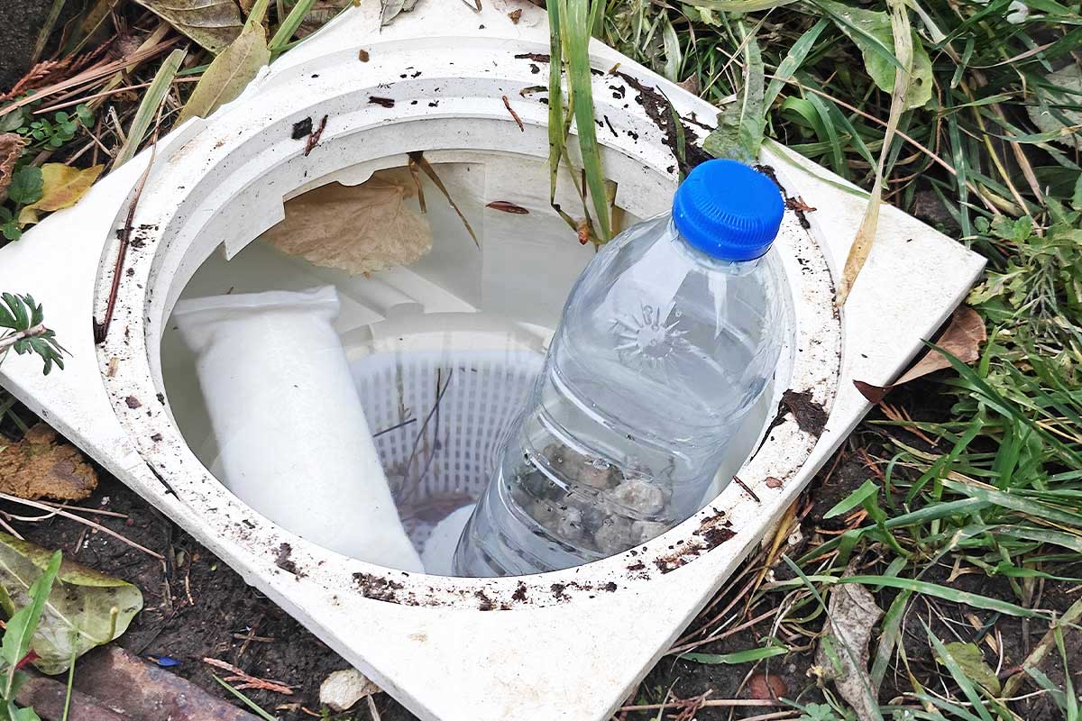 Une bouteille plastique avec des cailloux pour protéger le skimmer.