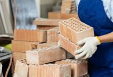 Une personne porte des briques en terre cuite.