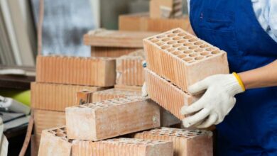 Une personne porte des briques en terre cuite.