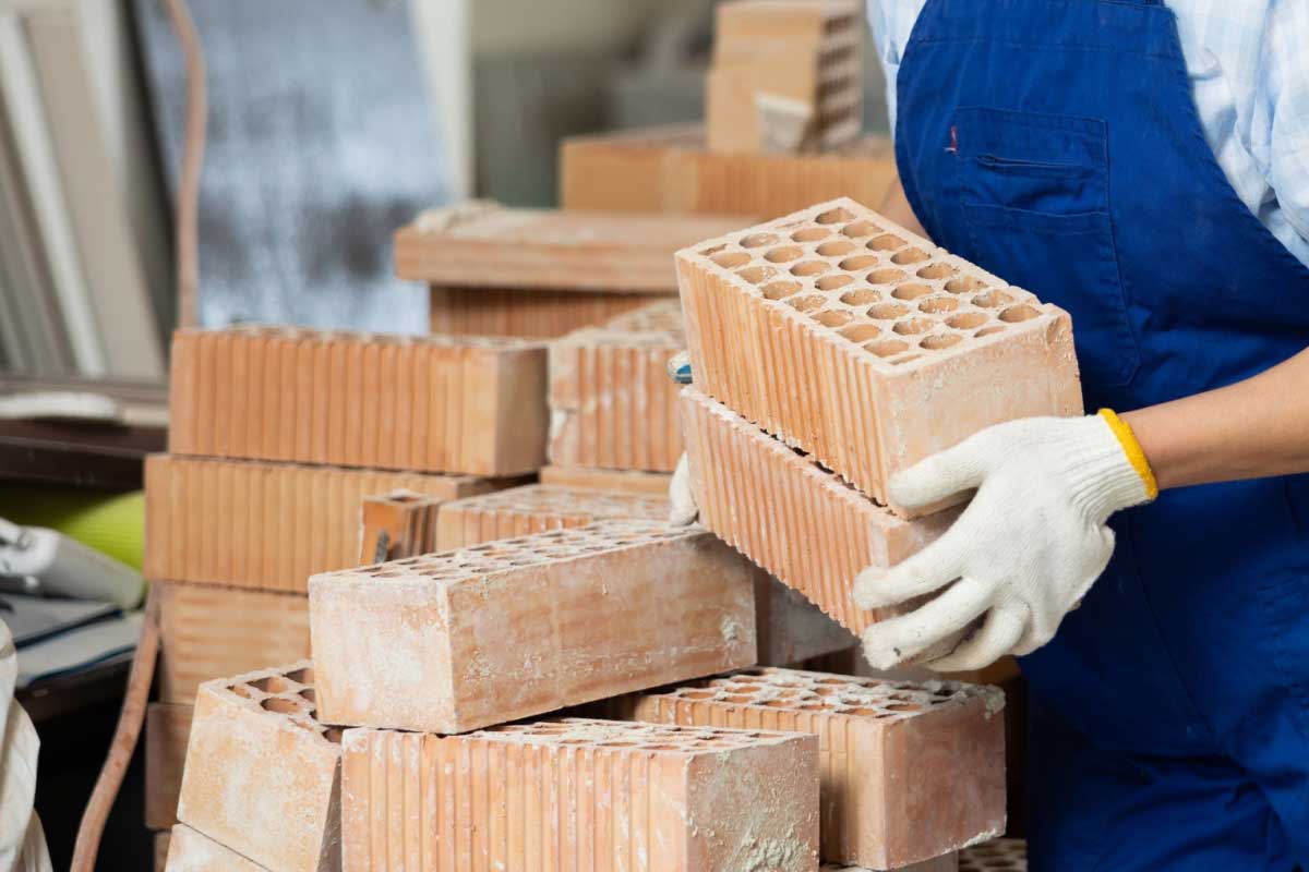 Une personne porte des briques en terre cuite.