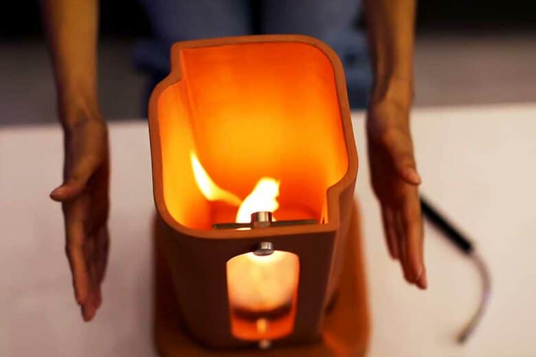 Une femme se réchauffe les mains autour de son chauffage d'appoint en terre cuite.