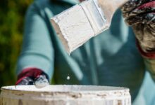 Un pinceau sort d'un pot de peinture blanche.