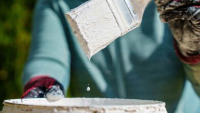 Un pinceau sort d'un pot de peinture blanche.