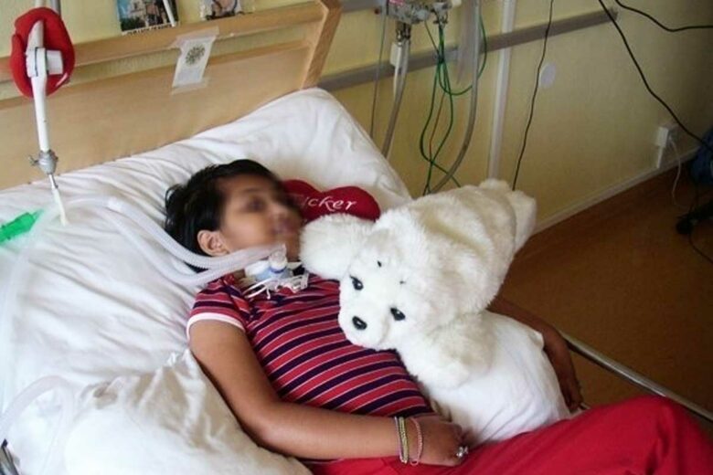 Un enfant hospitalisé avec le robot Paro sur son lit.