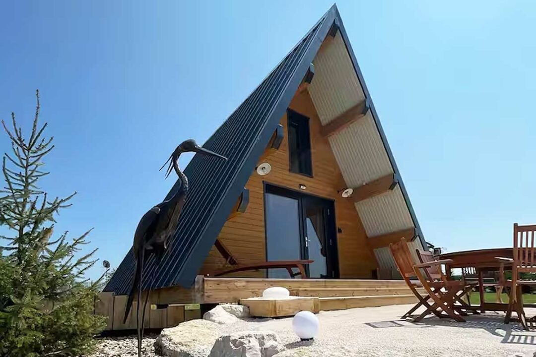 Une maison en A avec une sculpture à l'entrée.