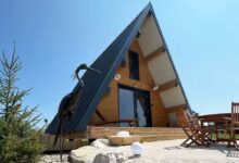 Une maison en A avec une sculpture à l'entrée.