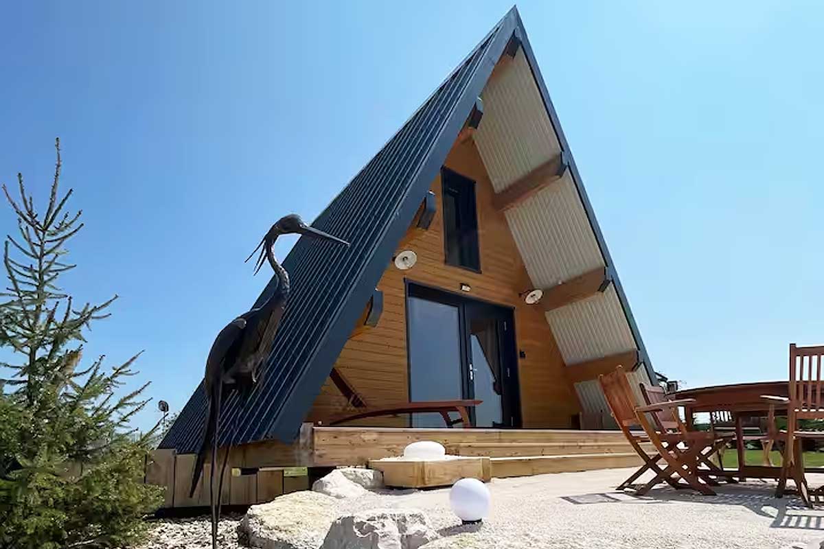 Une maison en A avec une sculpture à l'entrée.