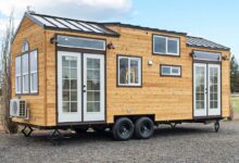 Une tiny house avec de multiples fenêtres sur une remorque à double essieu.