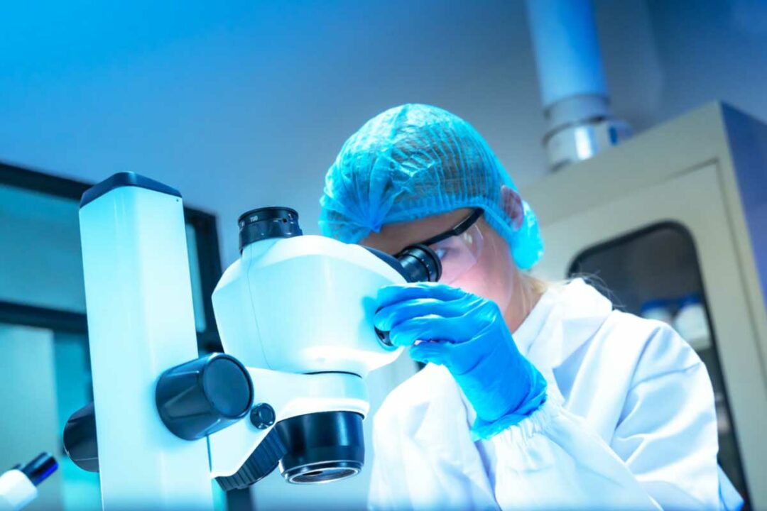 Une chercheuse sur un microscope.