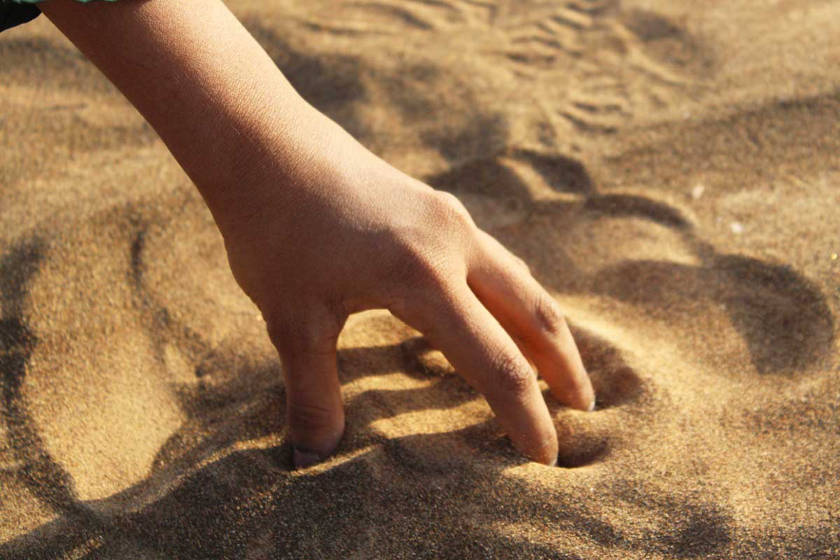 Une main dans du sable.