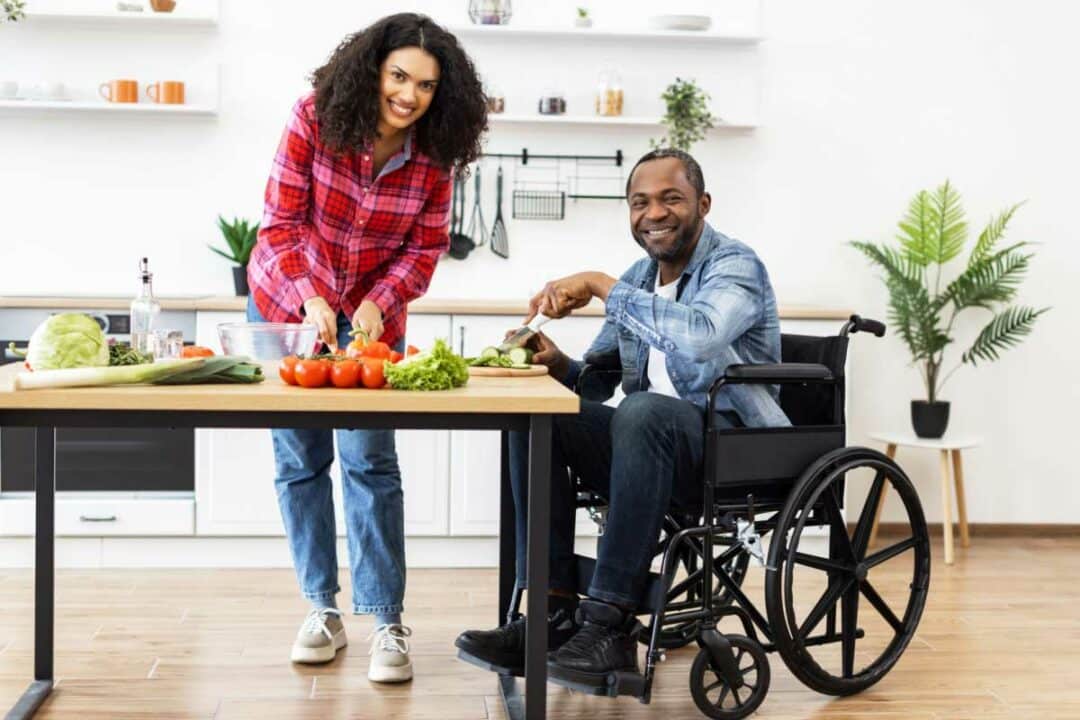 Un couple dont l'homme est en fauteuil roulant cuisine.