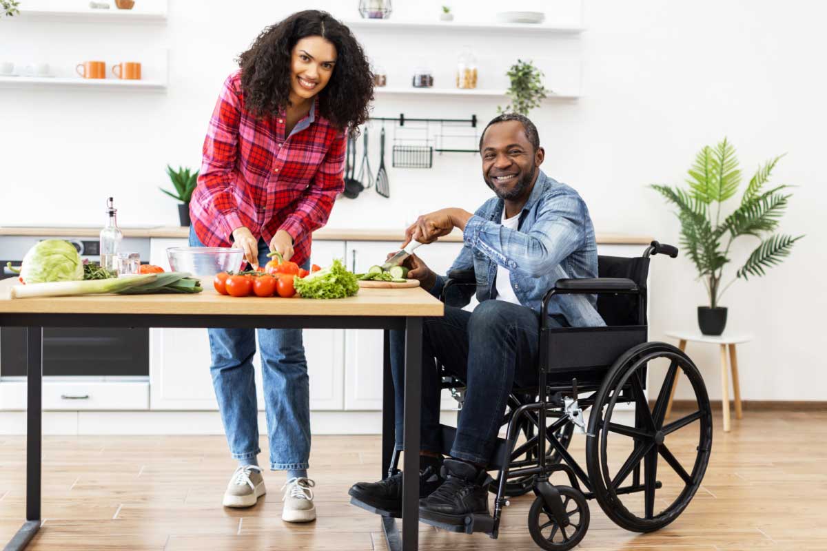 Un couple dont l'homme est en fauteuil roulant cuisine.