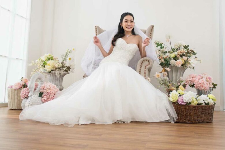 Une mariée assise entourée de fleurs.