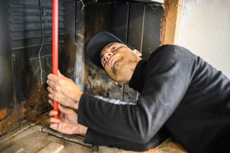 Un professionnel effectue le ramonage d'une cheminée.
