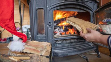 Une personne met une buche dans un poêle à bois.